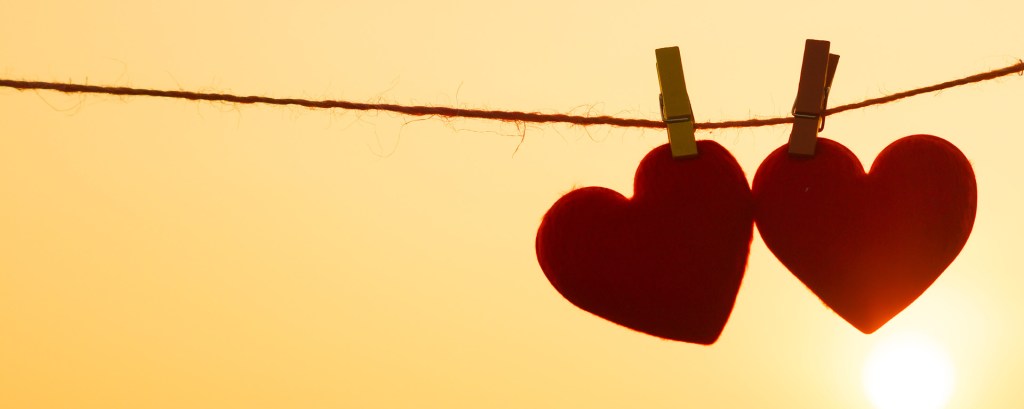 Two red paper hearts juxtaposed against the yellow sun