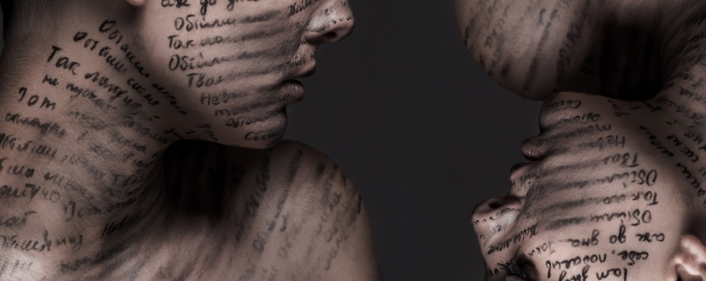 A female exposing her neck and left shoulder, has words written all over her skin